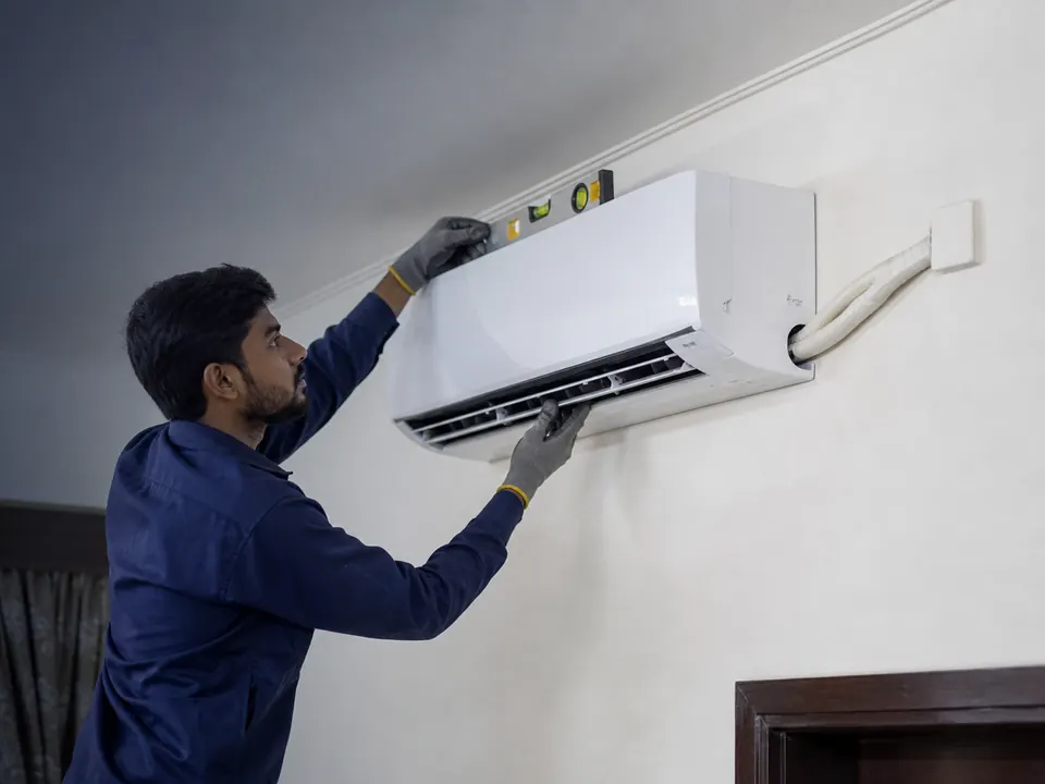 Technician fitting a new split air conditioner with a tidy pipe run