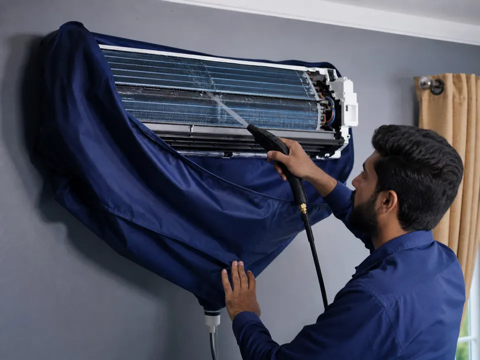 Technician deep-cleaning an installed split air conditioner