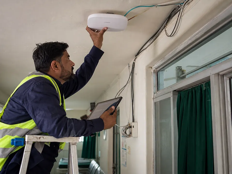Technician installing a ceiling WiFi access point