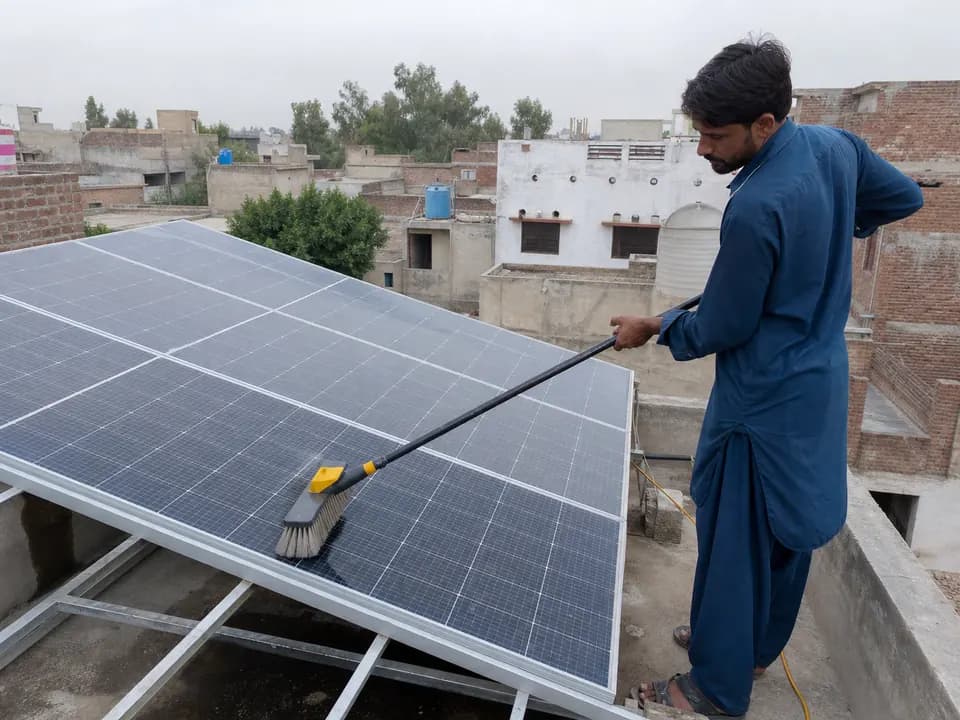 Technician cleaning dust from rooftop solar panels